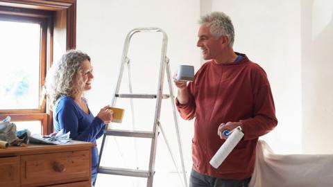 Couple drinking tea while decorating a room