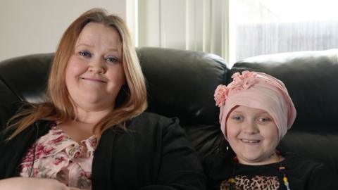 mum and daughter smiling for a picture together on the sofa 