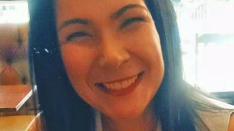 A woman with dark hair smiles at the camera