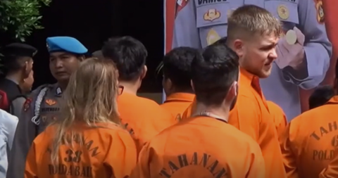 A group of people wearing orange prison suits