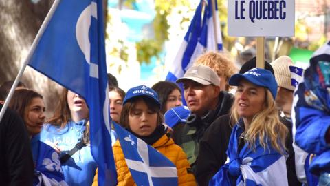 A rally for an independent Quebec, with a crowd of people in blue and white Fleurs de Lys Quebec flags