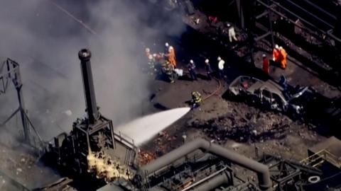 People use a hose to spay part of a steel plant