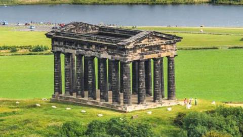 Aerial view of the monument. It is on top of a hill and is made up of 18 large stone columns in a rectangle supporting an ornate triangular roof, although the roof is totally open.