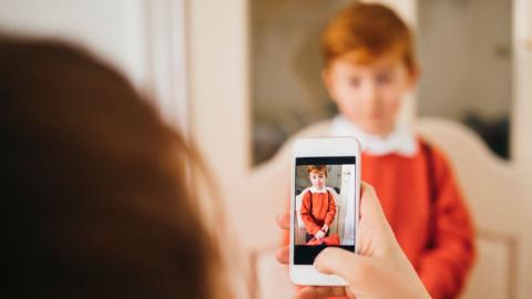 A person takes an image of a child with their mobile phone