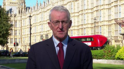 Hilary Benn stands in front of the houses of parliament in a suit talking to the ˿ remotely  