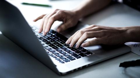 Hands typing on a laptop