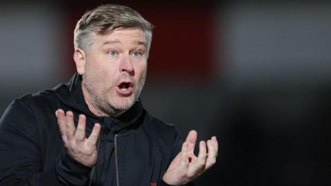 Karl Robinson stands on the touchline during a Salford City game