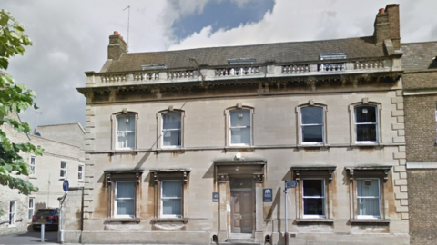 A large stone building with sash windows and a pale wooden door. 