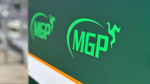 A large green sign with the MGP logo on it in pitlane.