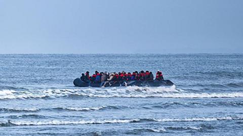 A boat in the English Channel with people on it, many wearing orange life jackets.