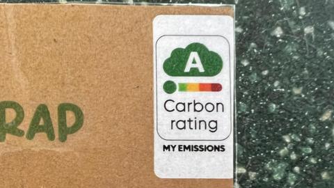 A sign with a carbon rating label on it with the green A cloud.