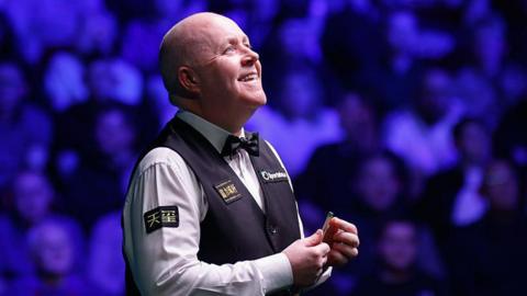 John Higgins looks up and smiles