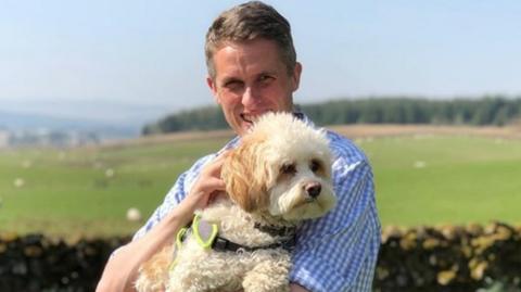 Gavin WIlliamson cuddling a dog