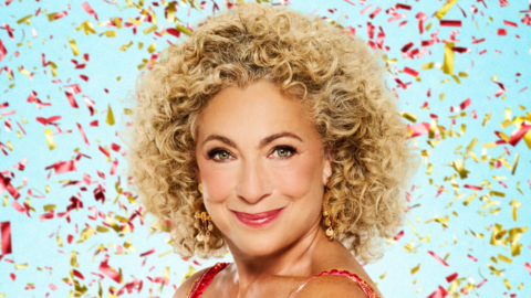 Alex Kingston has curly blonde hair and is standing in front of a blue wall whilst confetti falls behind her.