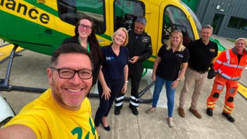 Mike Land and members of Wiltshire Air Ambulance in front of an air ambulance helicopter