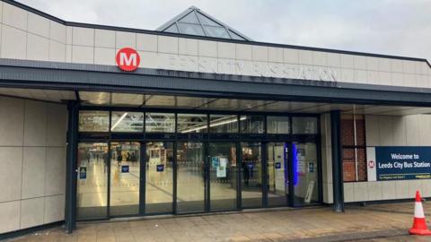 The Dyer Street entrance to Leeds bus station with automatic doors and an entrance sign. 