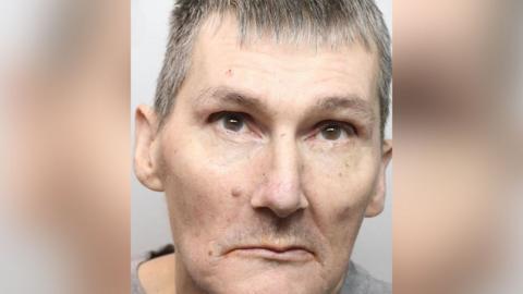 A police custody shot of Scott Thomson, who has short cropped grey hair and brown eyes.