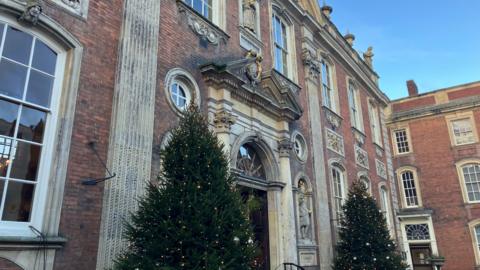 Two Christmas trees stand outside the main entrance to Worcester's Guildhall