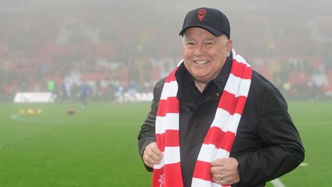 Ron Fowler with a Lincoln City cap and scarf on while stood on the pitch at the LNER Stadium