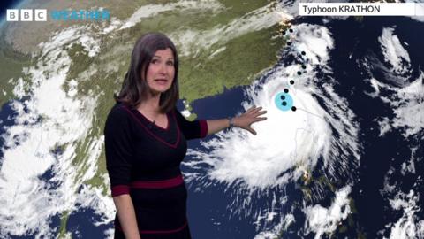 Helen Willetts standing in front of a weather map showing the path of Typhoon Krathon