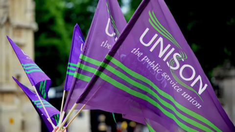 Purple and green flags which say 'Unison, the public service union' on them