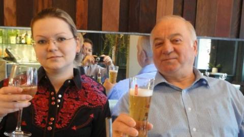 Yulia and Sergei Skripal pose for a photograph while sitting at a restaurant table holding drinks
