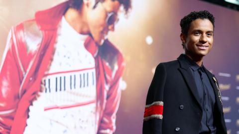 The King of Pop's real-life nephew, Jaafar Jackson, plays him in the movie. Jaafar is seen here standing in front of the movie poster.