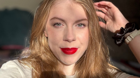 Fay Crockett is looking towards the camera with a slight smile. She has long blond hair and is wearing red lipstick