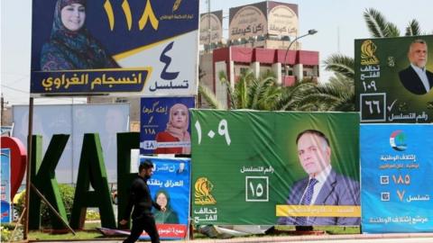 A man walks next to election campaign posters in Baghdad, Iraq