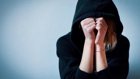 A girl hiding her face under a hooded jumper