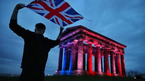 A man waves a Union Jack next to Sunderland's Penshaw Monument