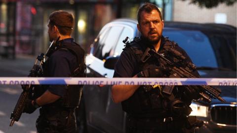 rmed police officers stand guard inside the cordon near Finsbury Park