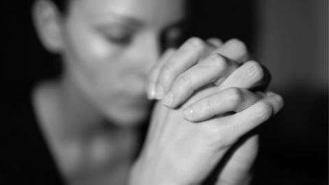 A young woman clasping her hands