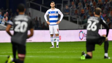 QPR player Dominic Ball stands while players from Rotherham take the knee