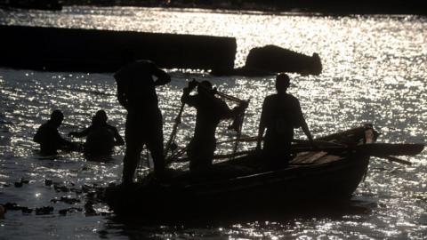 Fishermen in the Caribbean pull in a net onto their boat