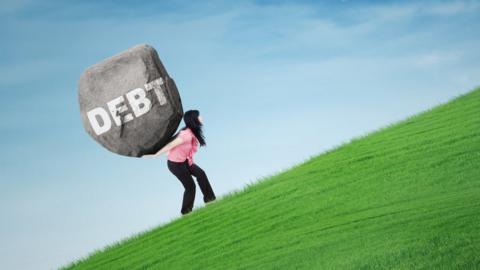 Woman climbing a hill carrying a large stone