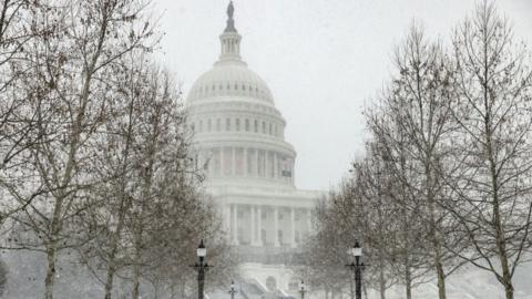 Pedestrians walk near the US Capitol building as snow falls during a winter storm