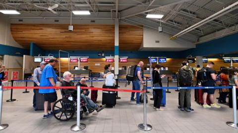 People wait in line at the airport, as they prepare to be evacuated from wildfires threatening the Northwest Territories town of Yellowknife, Canada, August 17, 2023. REUTERS/Jennifer Gauthier