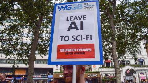 A protester holds a placard opposed to AI (Artificial Intelligence) replacing writers, at a protest organised by performing arts union Equity in solidarity striking US screenwriters.