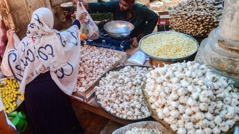 A customer buys vegetables from a stall at a market in Karachi