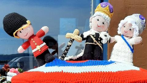 Their royal majesties and a knitted Buckingham Palace guard