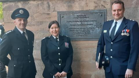 Firefighters standing next to a plaque