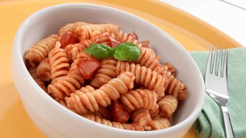 A bowl of pasts in a white bowl with a sprig of basil on top