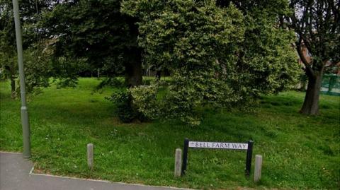 The Bell Farm Way road sign next to some trees