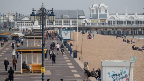 People make their way along Southsea Esplanade as they enjoy the warm weather in Southsea, Hampshire.