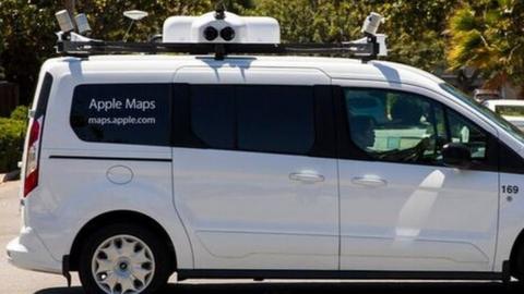 A picture of a white van with camera equipment on the roof and 'Apple Maps' written on it