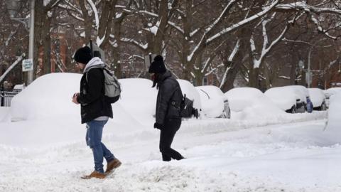 People walk down a snow covered street