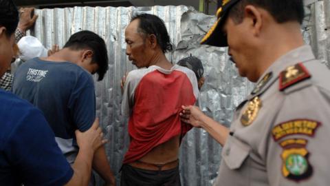 Police check two men standing against a wall on 9 July