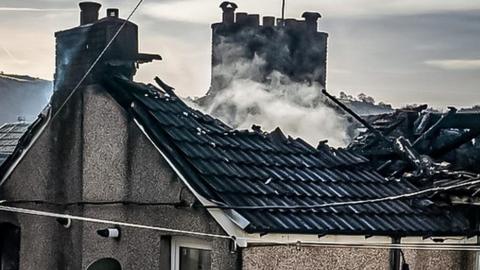 Burnt out roof of a home still smouldering
