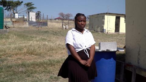 Yolanda standing in front of her home